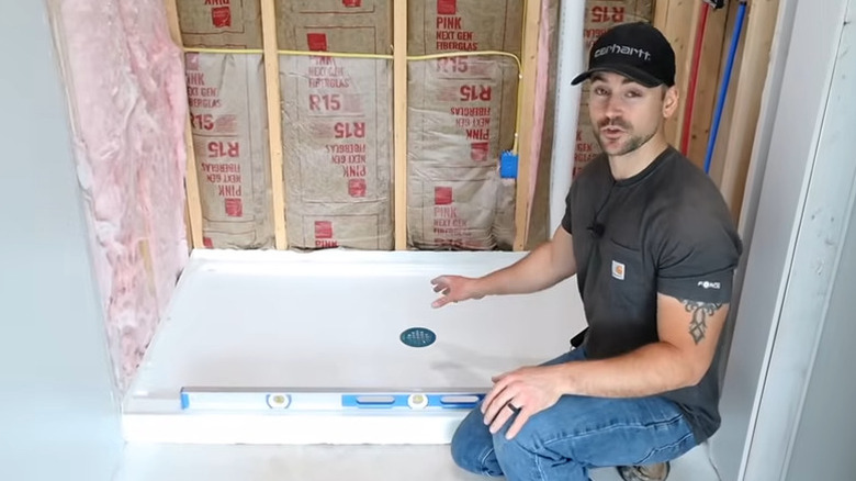 Somone showing off their fiberglass shower pan in the middle of a shower build.