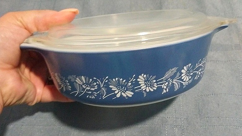 Close-up of a hand holding the Colonial Mist Pyrex casserole dish that's for sale on eBay