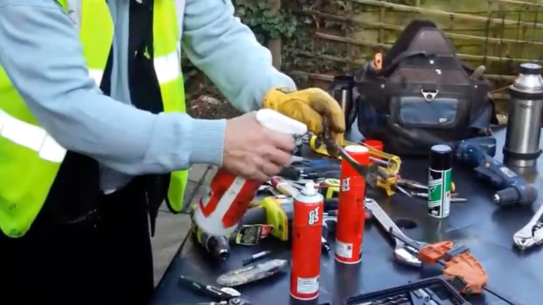 A worker cleans tools with a GT85 spray bottle.