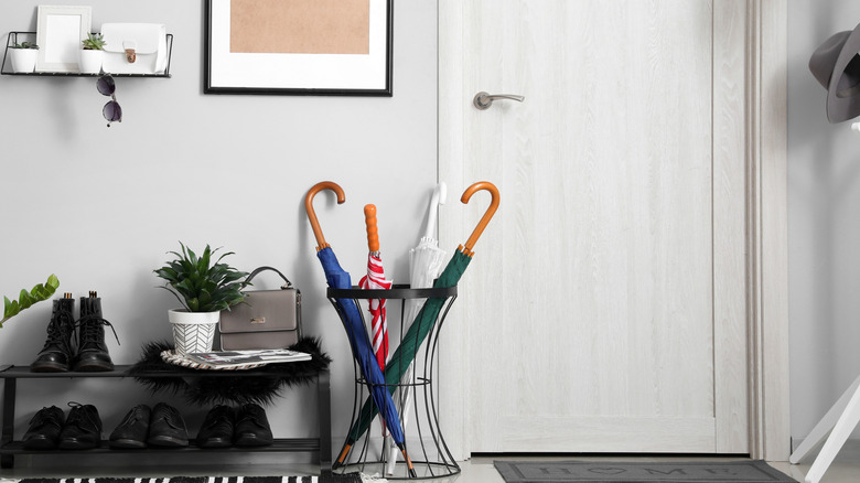 A deep, low-to-the-ground planter stand holds umbrellas by the entry door
