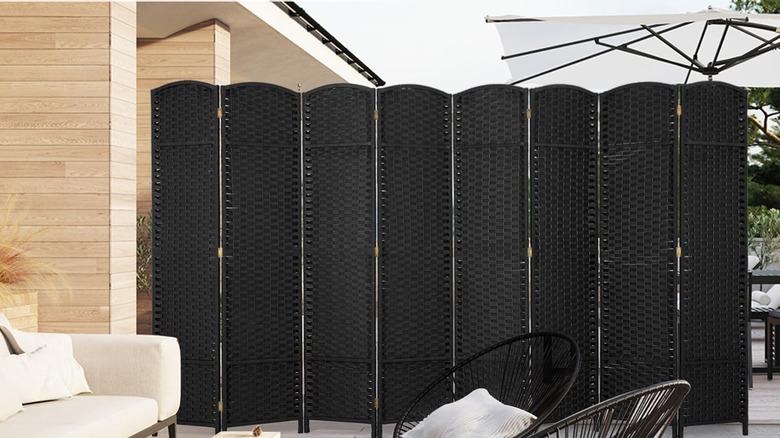 Black woven partition dividing outdoor porch area