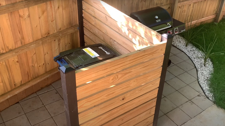 Matching wood garbage partition beside outdoor fence