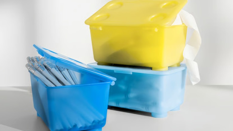 Blue and yellow IKEA GLIS containers full of pencils, pens, and paper tape.