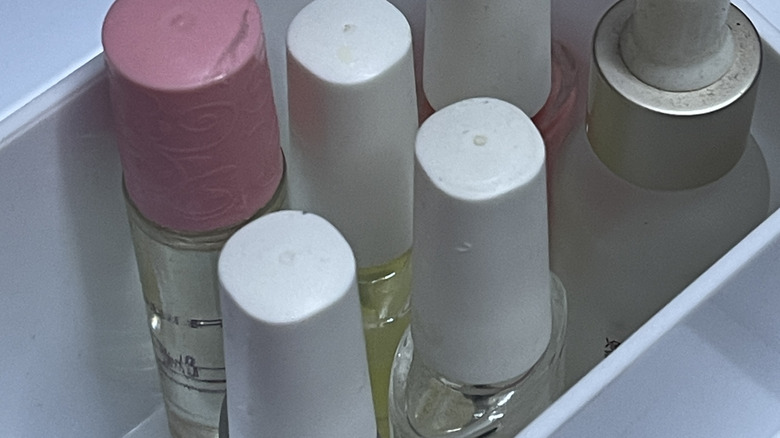 Bottles of nail polish stored in a large, clear IKEA GLIS box with divided compartments.
