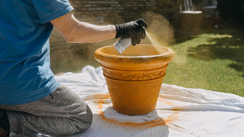 A person spray painting an old planter