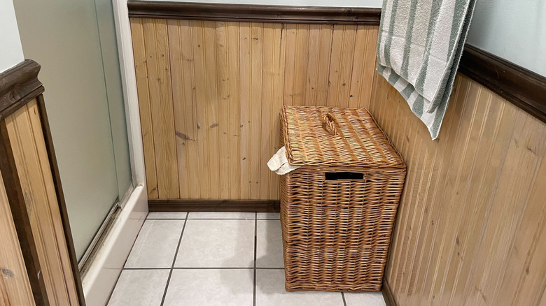 A laundry basket next to a shower in a bathroom.