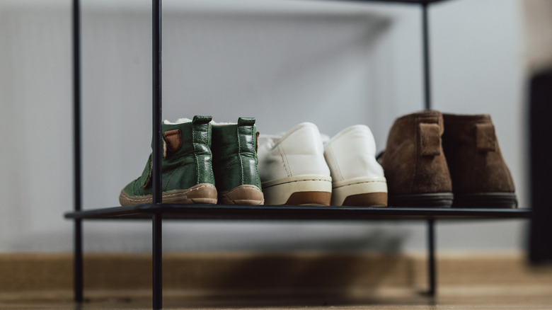 Metal shoe shelf filled with three pairs of shoes.