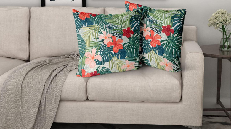A floral print throw pillow on a gray couch.