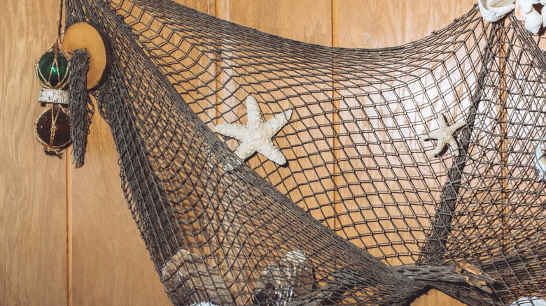 A wood panel wall with a fishnet and starfish hanging.