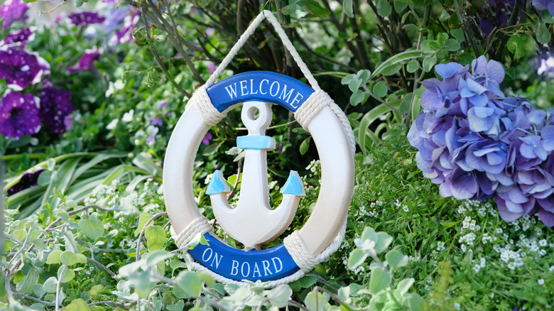 A welcome sign with an anchor in a garden.