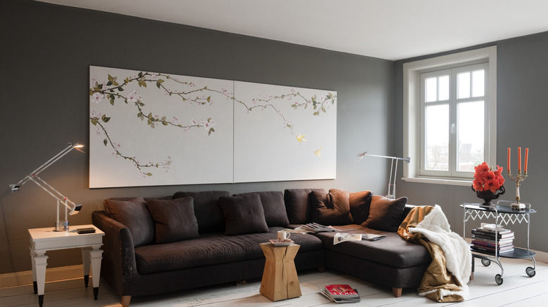 A living room with cool gray, dark walls, a sectional couch and eclectic furniture.