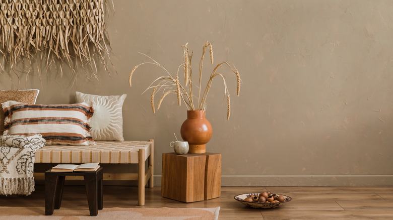 Room decor featuring grass elements and a woven bench with a throw blanket and pillows.