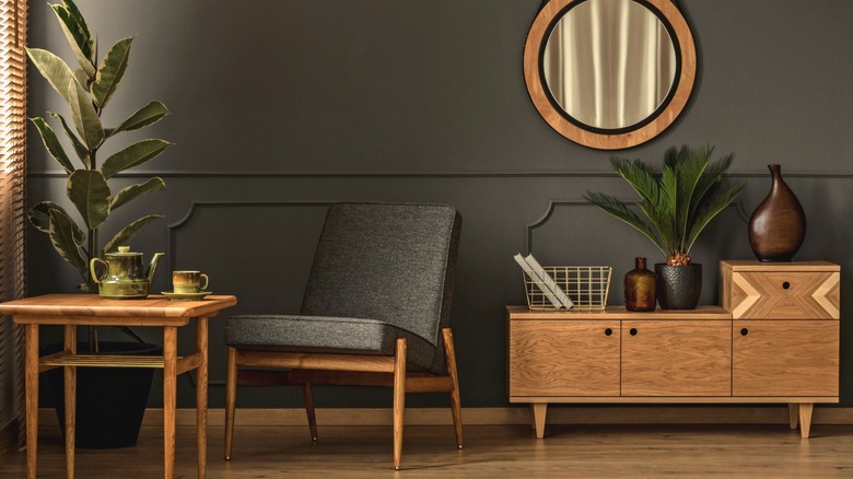 A living room set up with dark gray walls and warm wooden furniture.