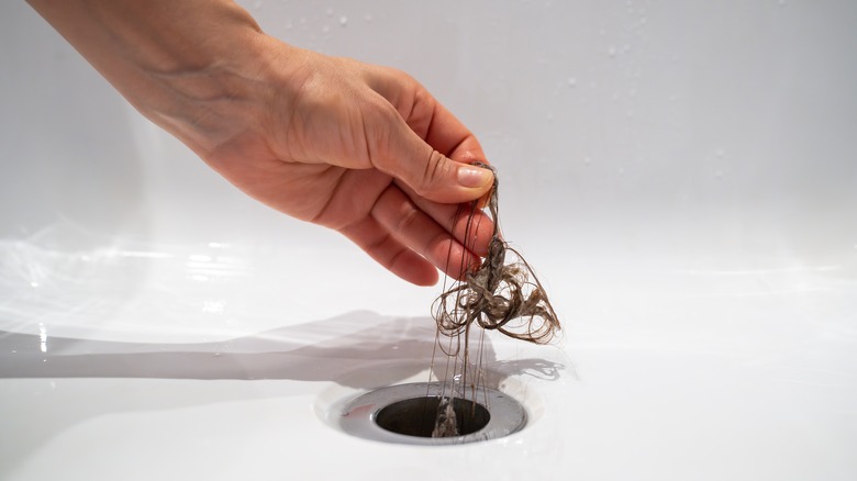 Hand removing wad of hair from drain