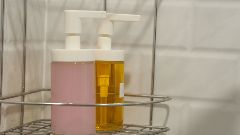 Two unlabeled body or hair care products in a metal shower caddy
