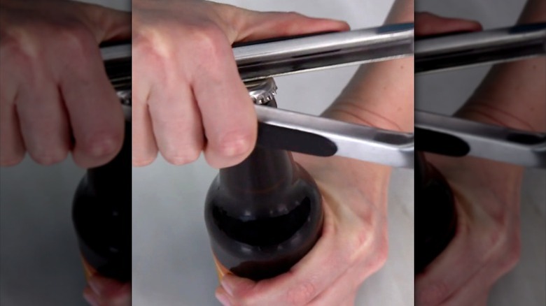 man opening beer bottle with old set of kitchen tongs
