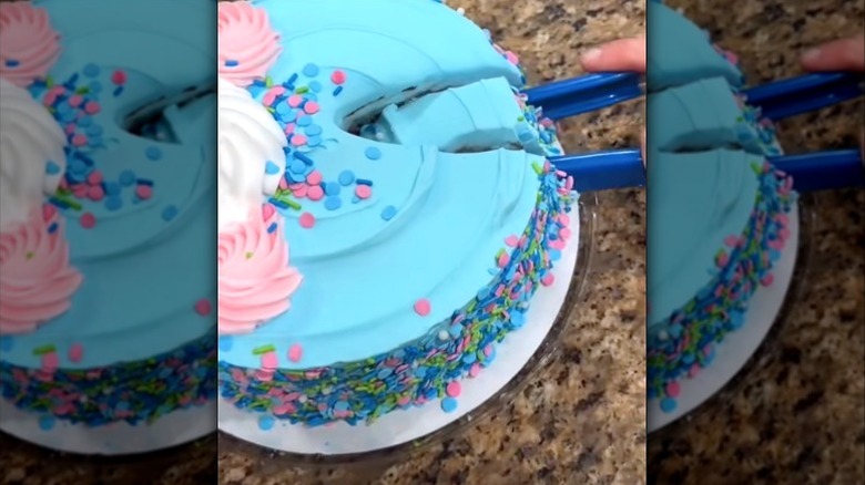 person cutting blue birthday cake with broken tongs