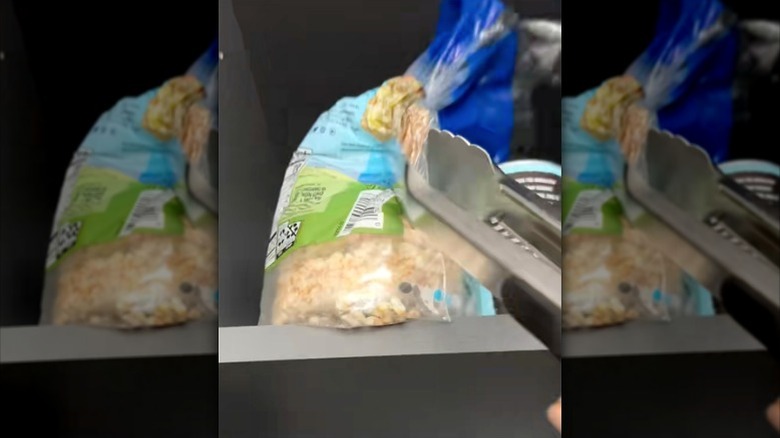 metal tongs grabbing pack of rice cakes from high pantry shelf