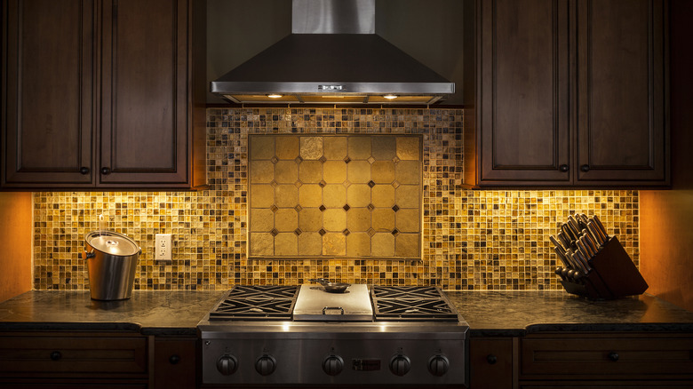 A dark kitchen with a mosaic backsplash.