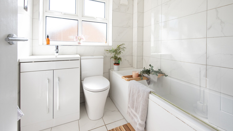 A modern white bathroom with large white tiles.