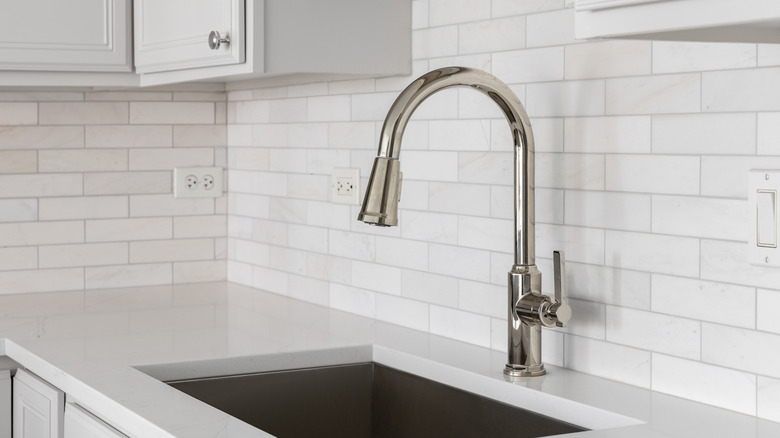 A kitchen sink with white subway tiles.