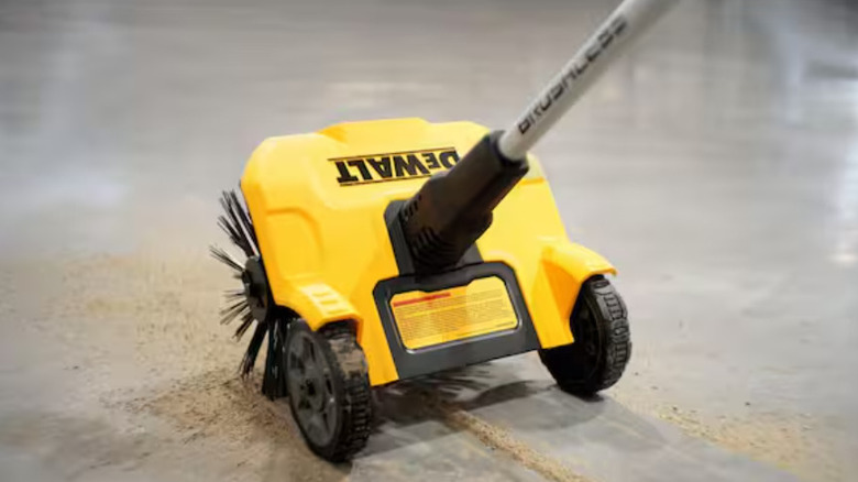The DeWalt electric sweeper being used on a dusty floor.