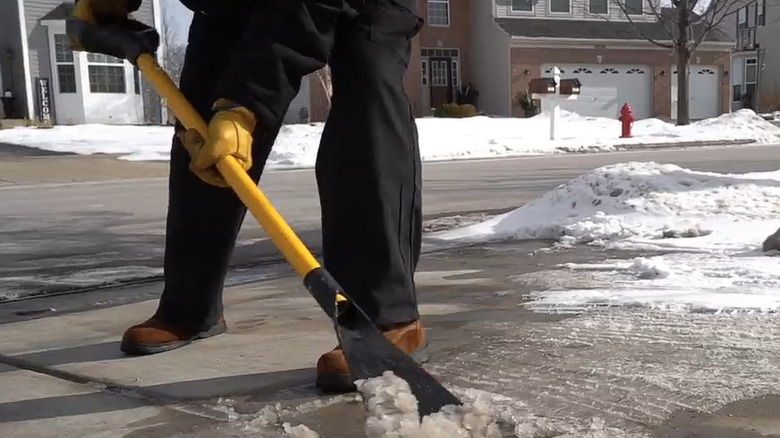 A man using the DeWalt ice scraper on a frosty sidewalk.