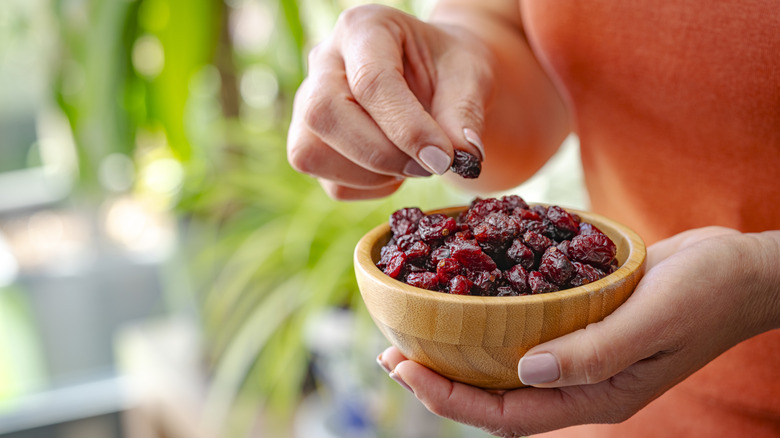 Close up of woman holding dried cranberries in bowl