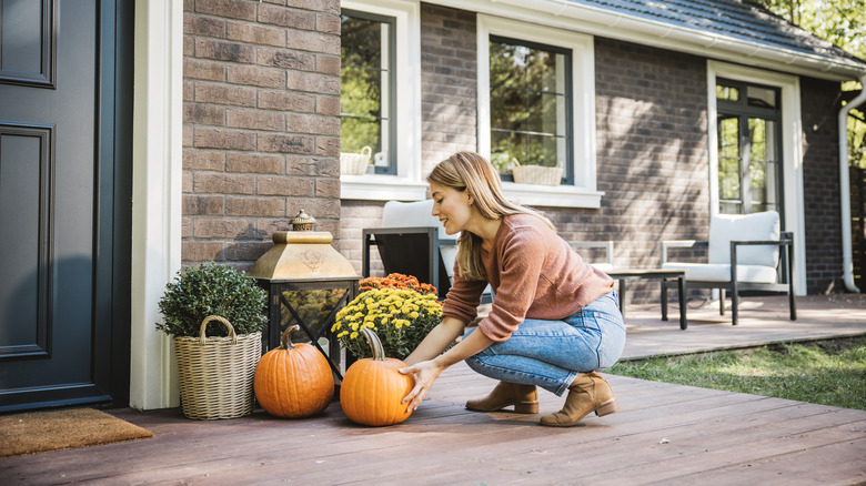 A person adding some fall decor to the front porch of a home