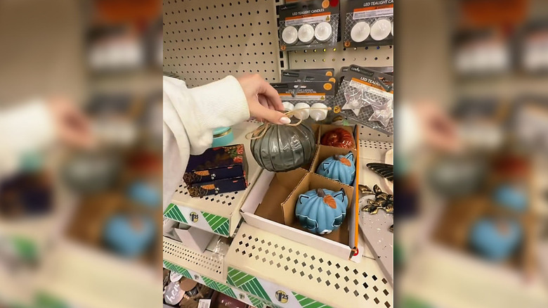 A shopper picks up a decorative black glass pumpkin inside a Dollar Tree store