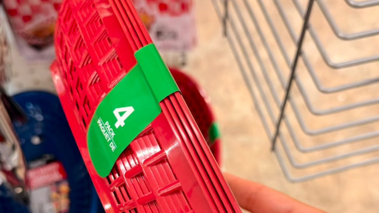 A person holds up a pack of red plastic baskets at a Dollar Tree in front of shelves that contain checkered wax paper liners
