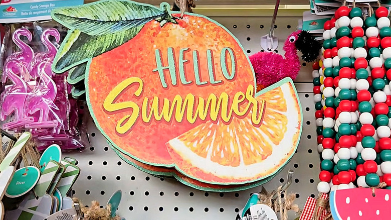 A summer-themed sign is displayed in the party decor aisle of a Dollar Tree
