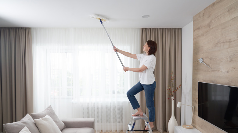 woman cleaning ceiling with mop