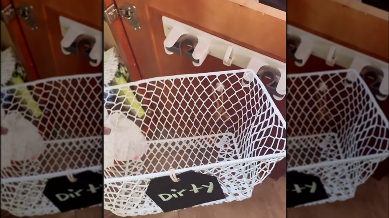 A Dollar Tree broom holder holds a basket for dirty cleaning supplies.