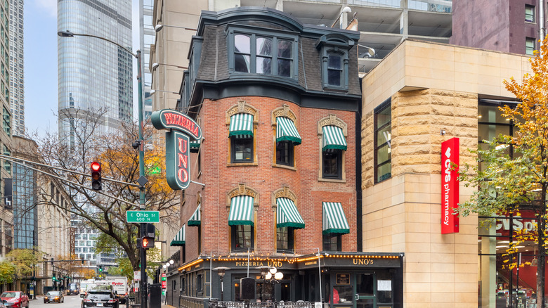 The Pizzeria Uno building with a lit-up sign and green and white awnings in Chicago.