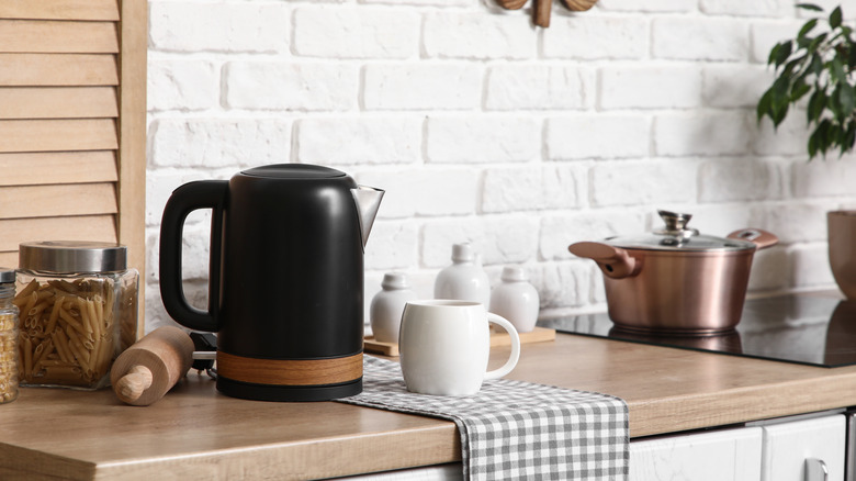 Electric kettle with cup on table in kitchen