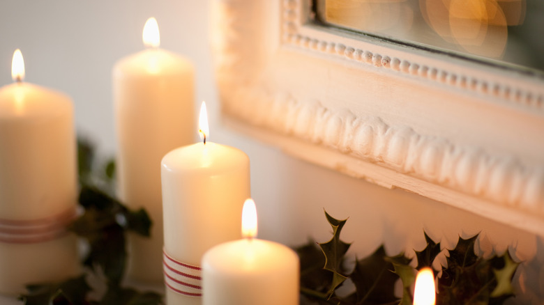 candles lit on a mantle next to a hanging picture in a frame