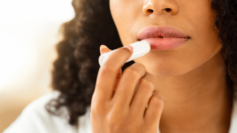 woman applying clear lip balm