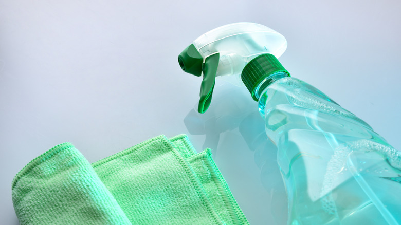 Blue cleaner in a spray bottle with a rag