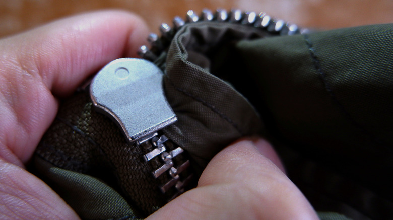 hand holding a zipper with fabric stuck in it