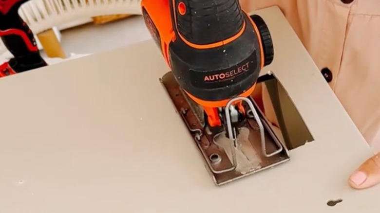 Person cutting through the back of the bin with a jigsaw