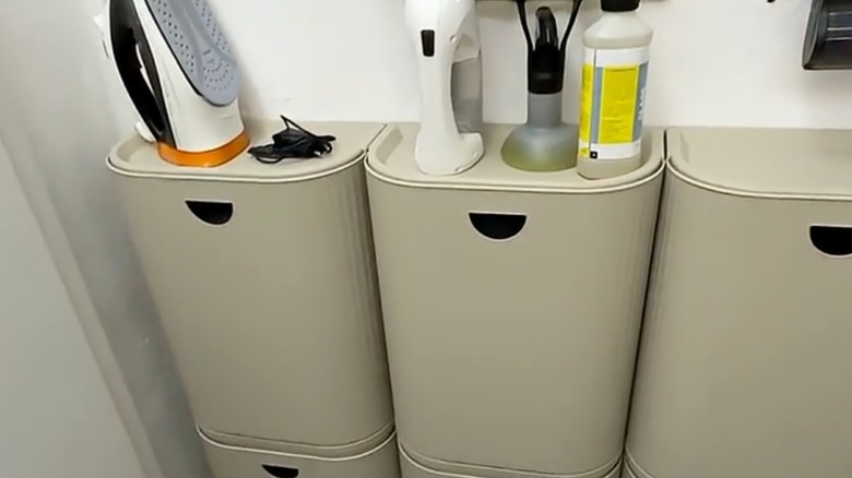 IKEA plastic bins on a wall with iron and steamer and cleaning supplies on top
