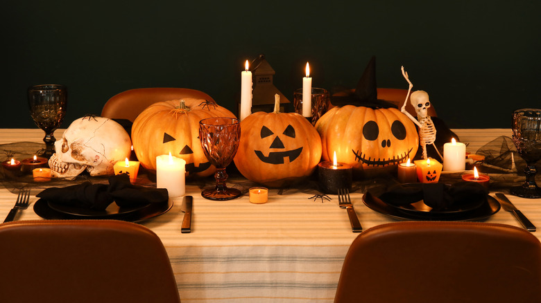 table decorated for Halloween with pumpkins and candles