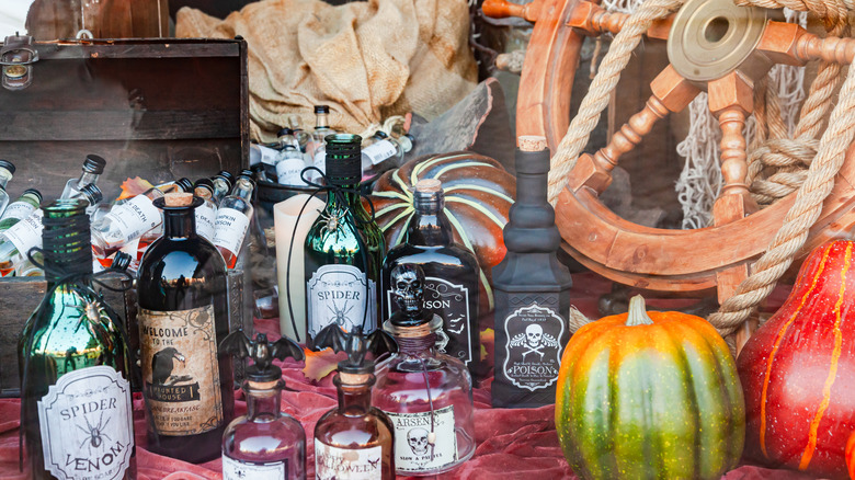 Halloween potion decorations made from bottles beside pumpkin