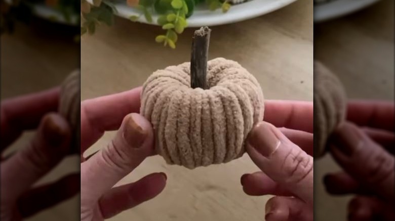 person holding mini pumpkin made from yarn