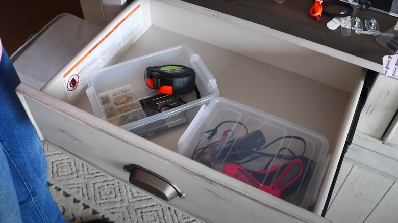 Tape measurer, glue gun, and other craft supplies in plastic bins in drawer