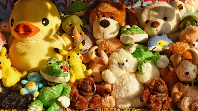 A variety of stuffed animals in a pile, including a duck, dog, bears and frogs