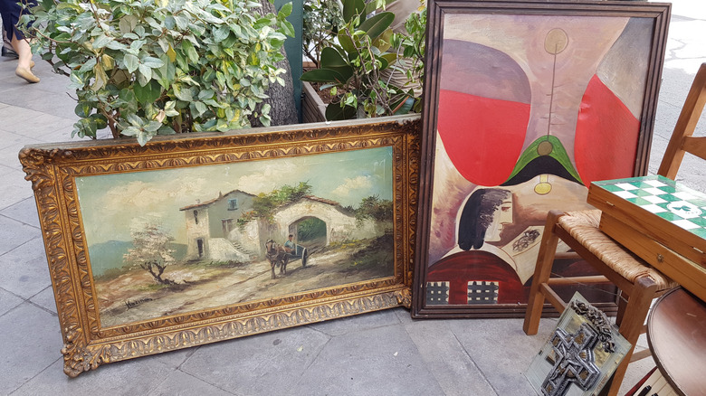 Two large framed art pieces laying against a plant