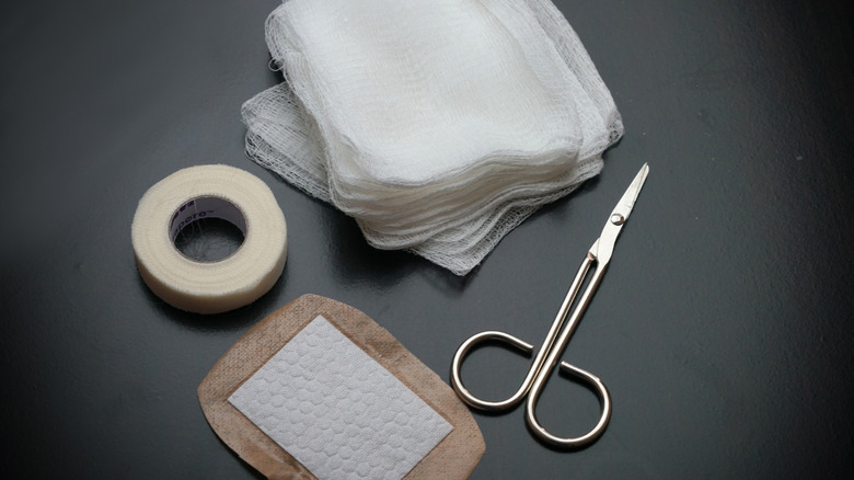 Opened bandages, gauze, tape, and scissors on a counter