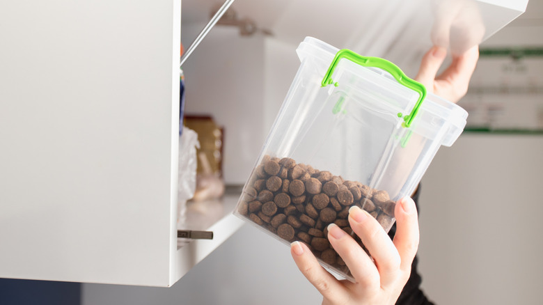 Pet food in plastic container being put away